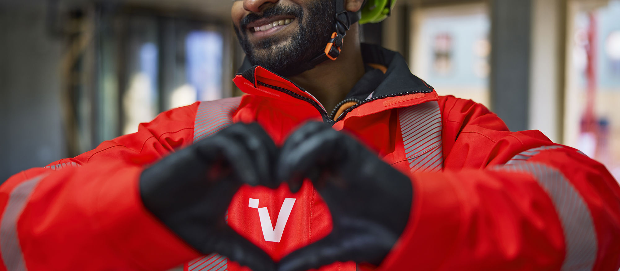 Man in Veidekke work gear forming a heart with his hands