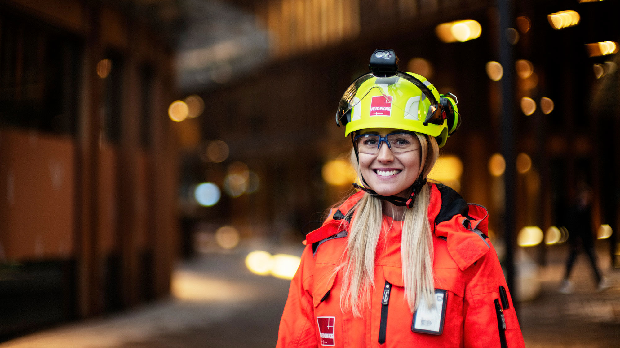 Woman with helmet and high-vis clothing smiling at camera. Photo.
