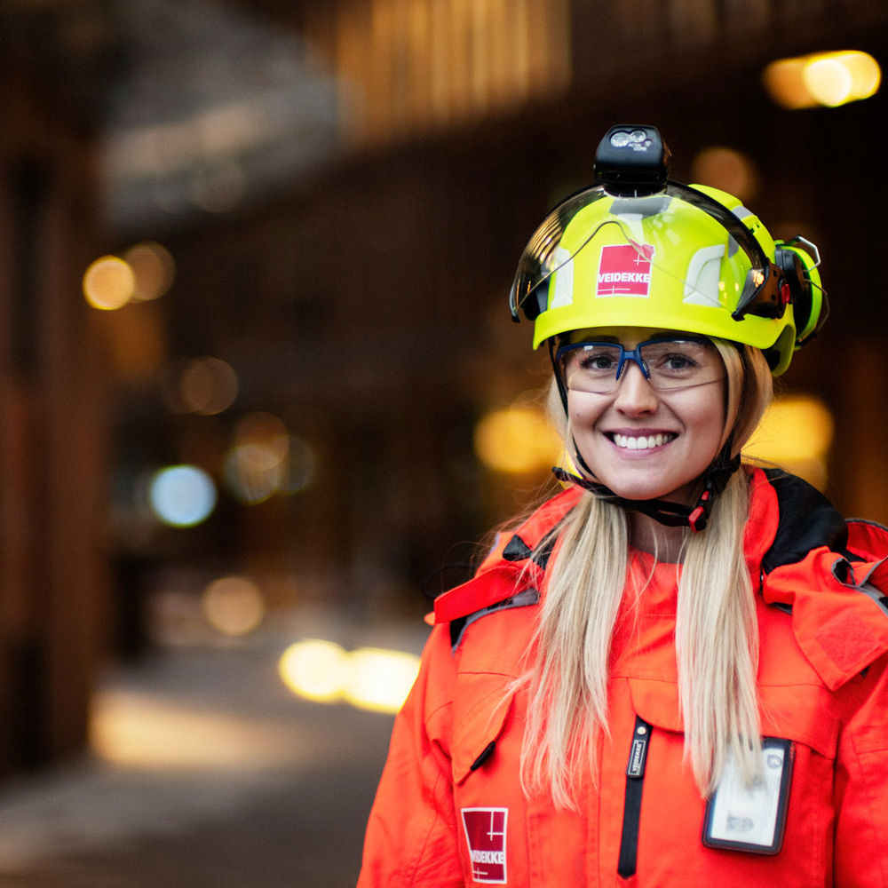 Woman with helmet and high-vis clothing smiling at camera. Photo.