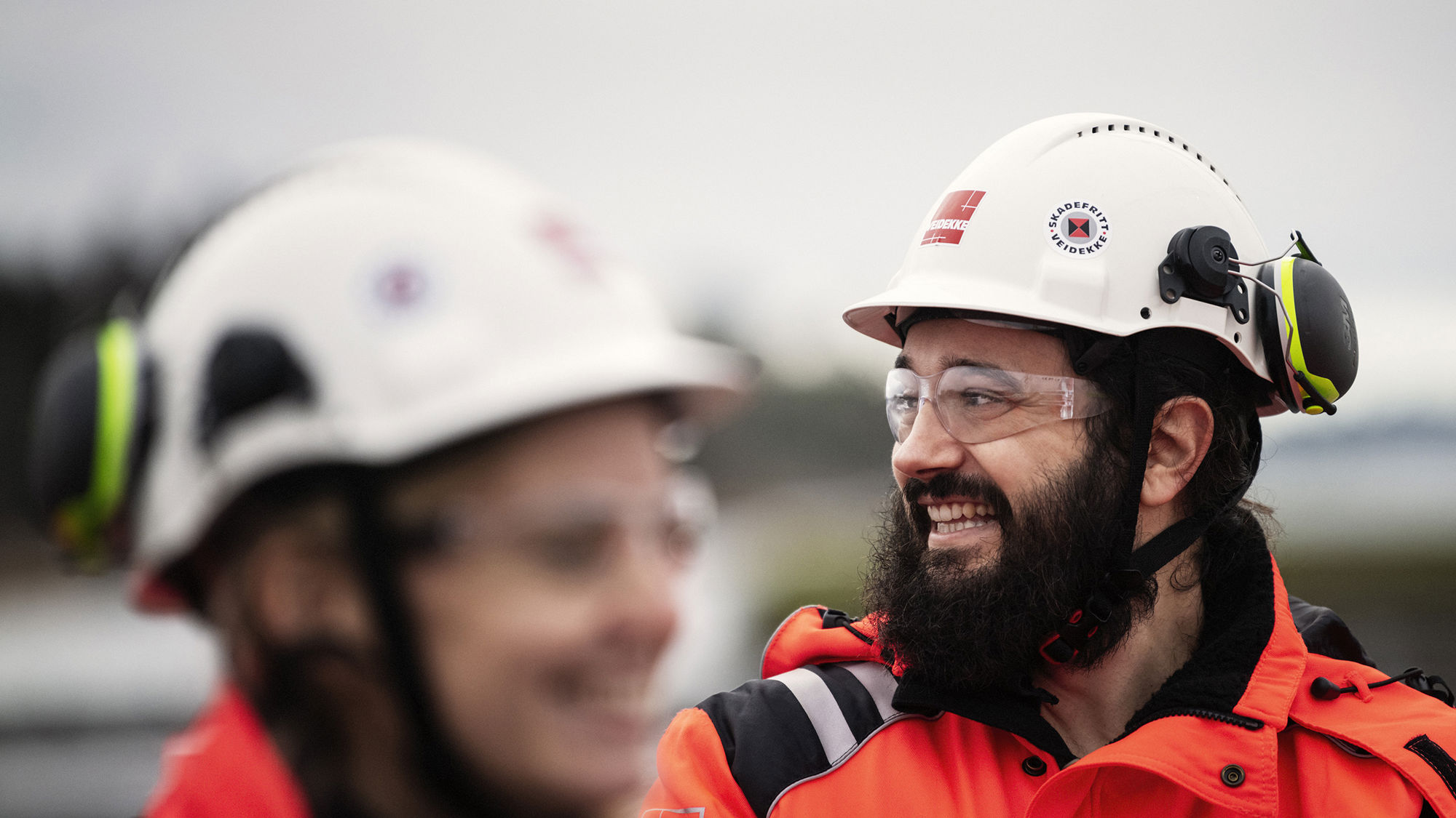 Man and woman wearing high-vis clothing and helmets. Photo.