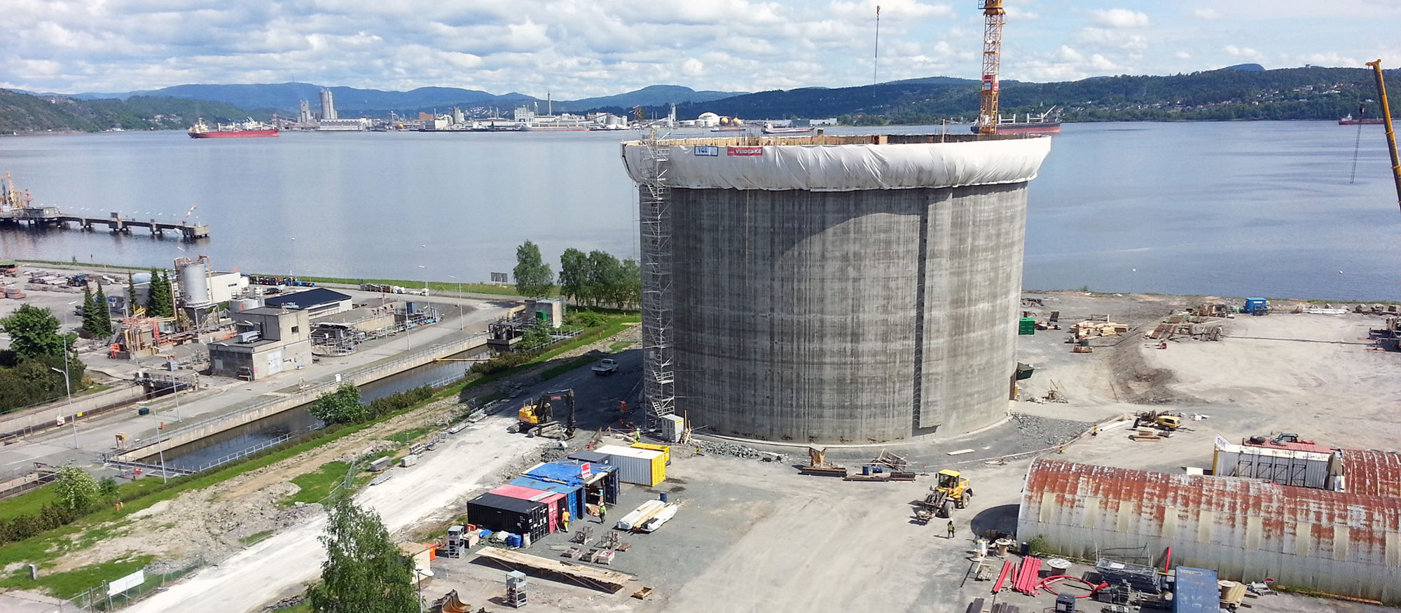 Ethane tank in concrete. Construction crane and views to the sea. Photo.