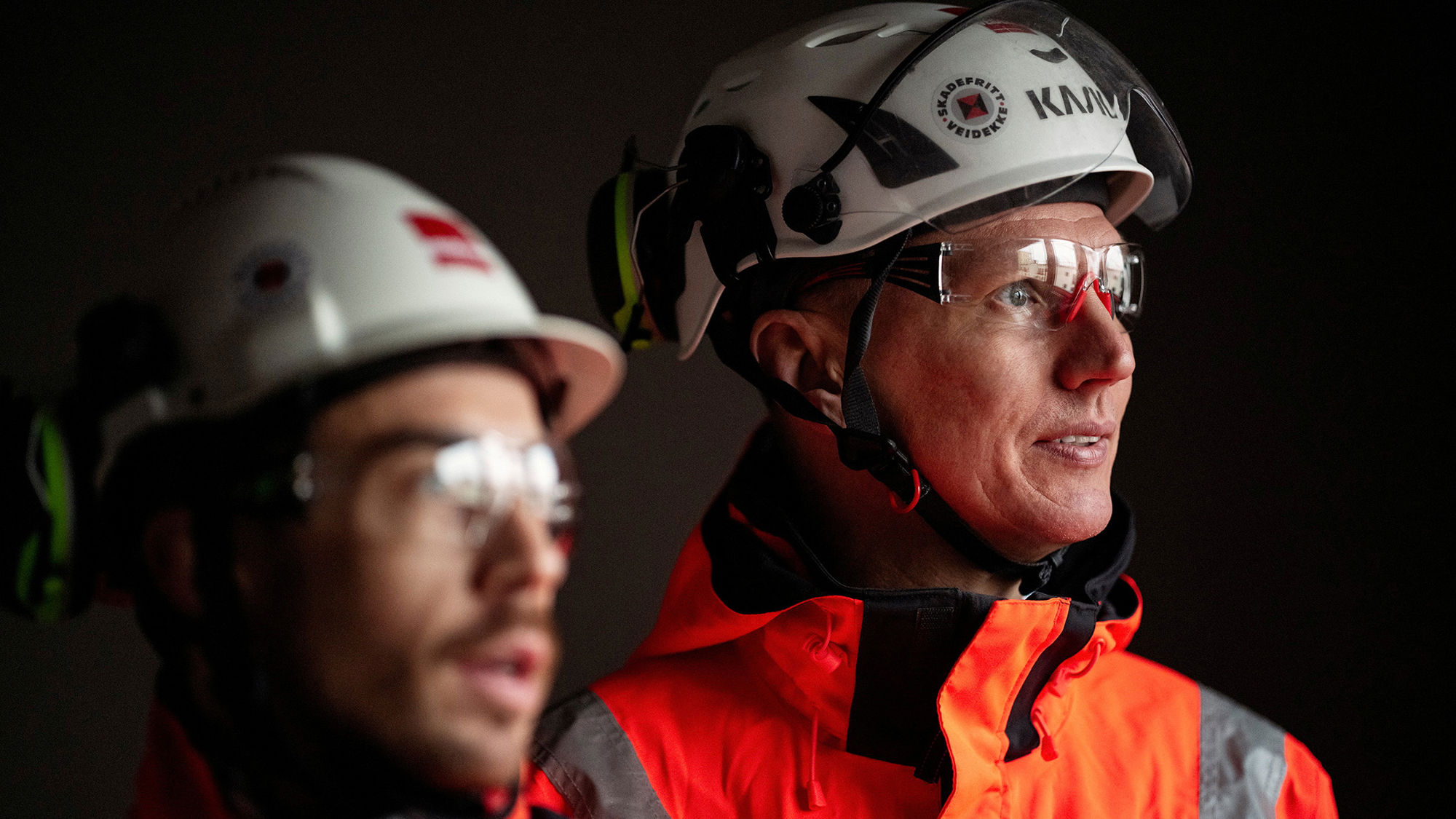 Two male workers looking at something. Wearing helmet and goggles. Photo.